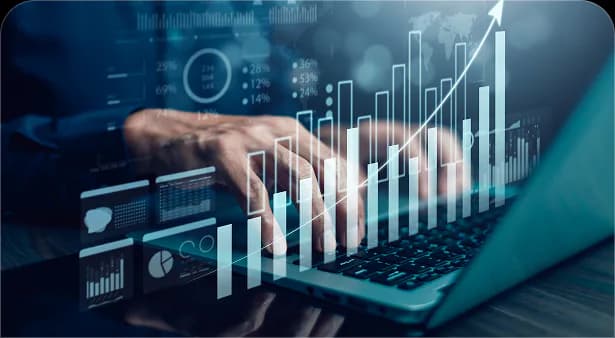 Hands on a laptop with rising sales charts and analytics