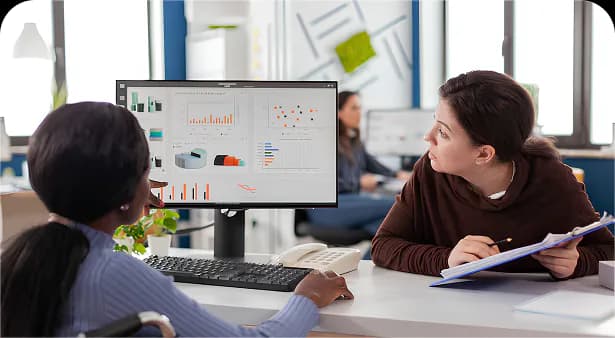 Two colleagues reviewing student analytics dashboards on a monitor